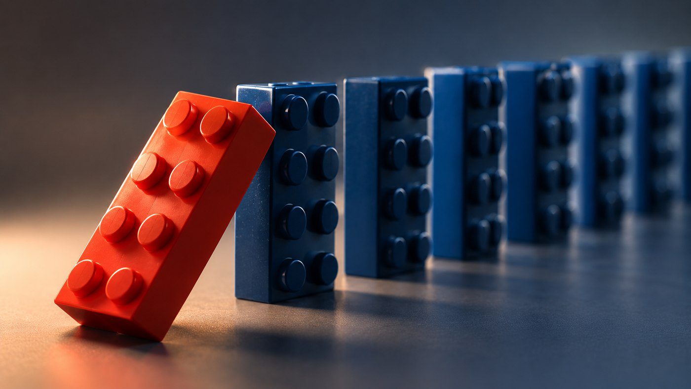 A red LEGO brick tipping over into a row of blue LEGO bricks like dominoes